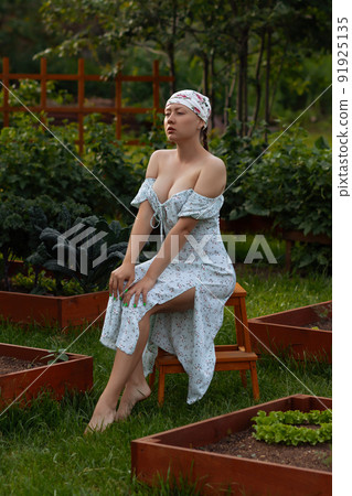 Sensitive woman sitting near garden beds 91925135