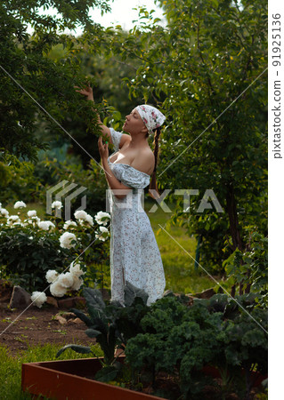 Woman examining branches in garden Woman examining branches in garden 91925136