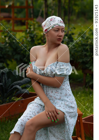 Sensitive woman sitting near garden beds 91925143