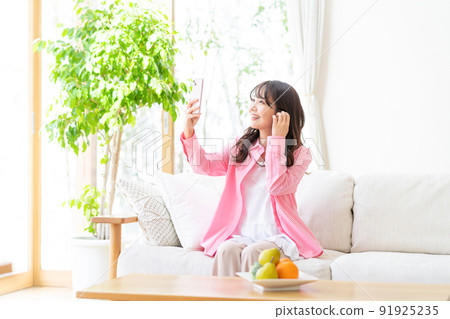 A young woman operating a smartphone in a room A young woman operating a smartphone in a room 91925235