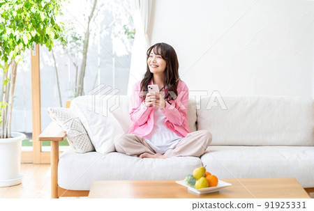 A young woman operating a smartphone in a room A young woman operating a smartphone in a room 91925331