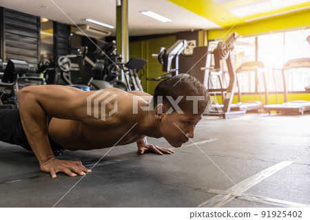 Young athletic man doing push-ups. Muscular and strong guy exercising. Young athletic man doing push-ups. Muscular and strong guy exercising. 91925402
