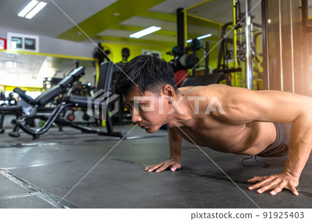 Young athletic man doing push-ups. Muscular and strong guy exercising. Young athletic man doing push-ups. Muscular and strong guy exercising. 91925403
