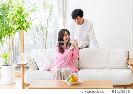 A couple operating a smartphone in the living room A couple operating a smartphone in the living room 91925938