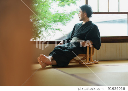 A man in kimono sitting on a sitting chair A man in kimono sitting on a sitting chair 91926036