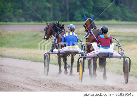 Women jockeys walk their horses on chariots on a summer day. Women jockeys walk their horses on chariots on a summer day. 91929543