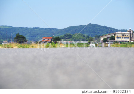 A scene where the scenery is swaying in the heat of the heat in the distance of the asphalt road surface under the scorching sun of summer 91932384