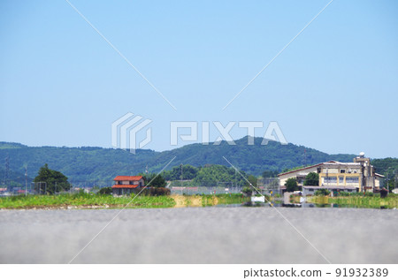 A scene where the scenery is swaying in the heat of the heat in the distance of the asphalt road surface under the scorching sun of summer 91932389