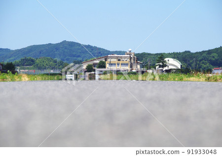 A scene where the scenery is swaying in the heat of the heat in the distance of the asphalt road surface under the scorching sun of summer 91933048