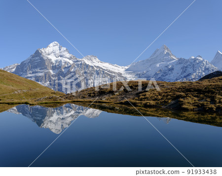Rocky mountains and reflection on the surface of the lake. Landscape in Grindelwald, Switzerland. Rocky mountains and reflection on the surface of the lake. Landscape in Grindelwald, Switzerland. 91933438
