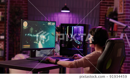 Handheld shot of gamer girl celebrating winning first place in action space game while man is playing first person shooter in virtual reality. Couple online gaming simulation using pc and vr goggles. 91934459
