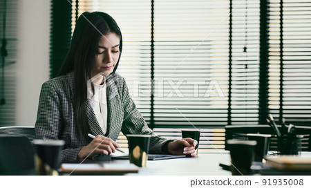 Pensive professional financial advisor working with statistics document at her office Pensive professional financial advisor working with statistics document at her office 91935008