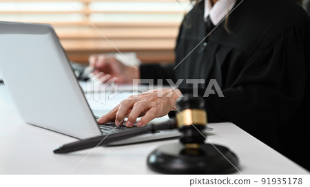 Senior female lawyer reading judiciary law document and using laptop at her workplace 91935178