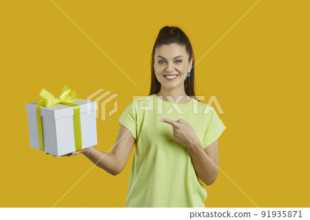 Smiling woman point at wrapped gift box 91935871