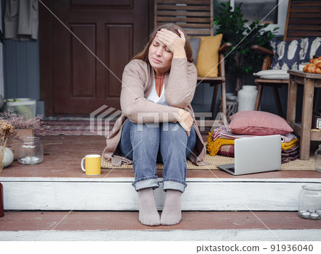 middle aged depressed woman sitting on porch. 91936040