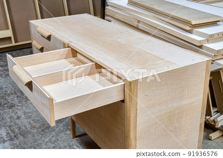 Chest of drawers made of solid alder with open drawer in process of production at workshop. Creation of modern domestic furniture for bedroom interior 91936576