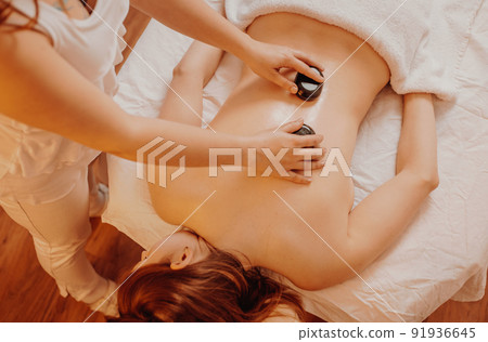 Woman making massages by lava stones in a beauty saloon, lifestyle and healthcare concept 91936645