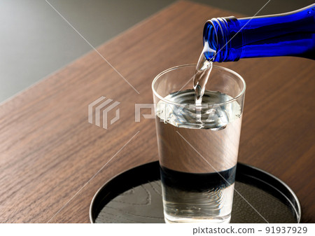 Pour sake into a glass of cold sake Pour sake into a glass of cold sake 91937929