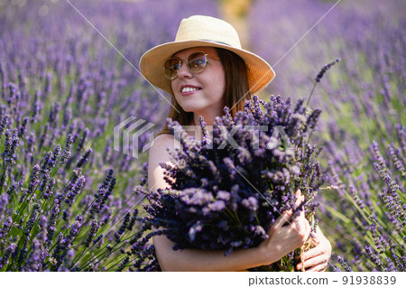 A young woman in a straw hat with a bunch of lavender flowers. A young woman in a straw hat with a bunch of lavender flowers. 91938839