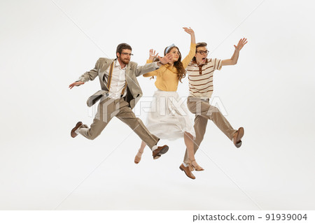 Portrait of cheerful young people, friends posing in motion isolated over white studio background. Stylish retro look Portrait of cheerful young people, friends posing in motion isolated over white studio background. Stylish retro look 91939004