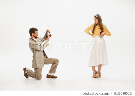 Portrait of young man taking photo of beautiful young women with retro camera isolated over white background 91939006