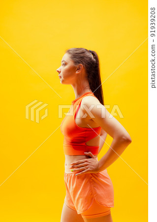 Profile view of young girl wearing summer sports style outfit isolated on bright yellow background. Sport, health, active lifestyle Profile view of young girl wearing summer sports style outfit isolated on bright yellow background. Sport, health, active lifestyle 91939208
