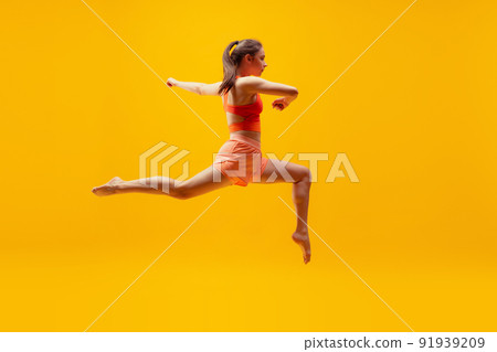 Full-length portrait of young slim girl running isolated on bright yellow background. Modern sport, action, motion, summer, vacation, youth concept. Full-length portrait of young slim girl running isolated on bright yellow background. Modern sport, action, motion, summer, vacation, youth concept. 91939209