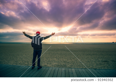 Silhouette of man on the beach looking at magical dramatic sunset. Man with hands in the air standing on the wooden terrace Silhouette of man on the beach looking at magical dramatic sunset. Man with hands in the air standing on the wooden terrace 91940302