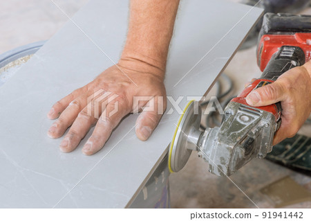 Worker using angle grinder polishing disk with diamond for polishing cut corner tiles 91941442