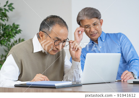Two senior men with presbyopia looking at a computer wearing glasses in the living room at home Two senior men with presbyopia looking at a computer wearing glasses in the living room at home 91941612