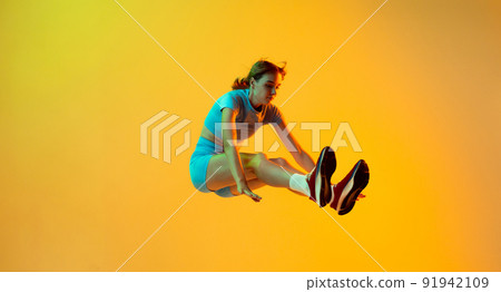 Professional longjumper. One female athlete in sports uniform jumping isolated on yellow background. Concept of sport, action, motion, speed. Professional longjumper. One female athlete in sports uniform jumping isolated on yellow background. Concept of sport, action, motion, speed. 91942109