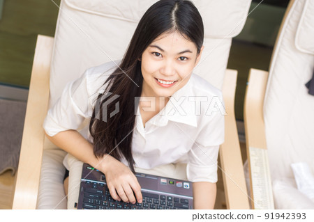 Business women sitting on sofa wooden chair use laptop computer in modern room Business women sitting on sofa wooden chair use laptop computer in modern room 91942393