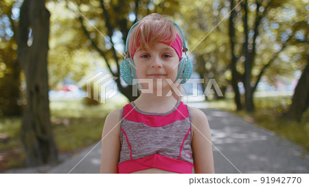 Portrait of athletic sport runner child girl training, listening favorite music song in headphones Portrait of athletic sport runner child girl training, listening favorite music song in headphones 91942770