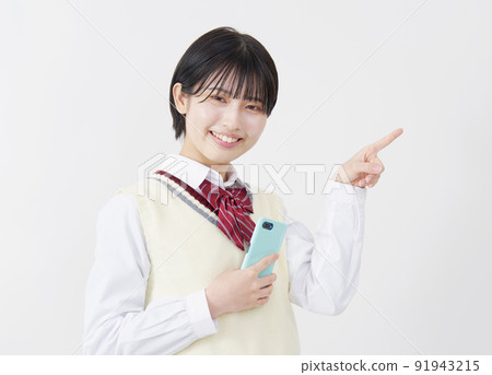 拿著智能手機並且指向右邊白色背景的高中女孩 91943215