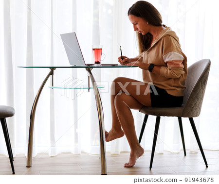 Young woman working online with laptop at home 91943678