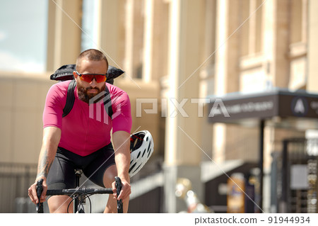 Caucasian handsome young man in protective helmet goes out for bicycle ride through city streets on blurred background. Cyclist male ride bike outdoors in urban. 91944934