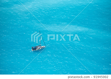 Aerial view over a boat on turquoise sea water, in sunny summer day in Ioniam Sea, Greece 91945002
