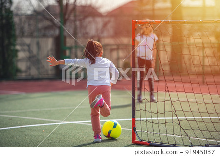 Happy little girl playing football in spring sunny day. Childhood, leisure games and people concept 91945037