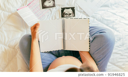 Pregnant writing baby list. Beautiful pregnancy woman writing check list. Happy pregnant lady holding notepad. Pregnancy, maternity, healthcare concept. Pregnant writing baby list. Beautiful pregnancy woman writing check list. Happy pregnant lady holding notepad. Pregnancy, maternity, healthcare concept. 91946825