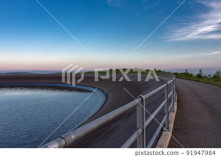 Upper water reservoir of the pumped storage hydro power plant Dlouhe Strane in Jeseniky Mountains, Czech Republic. During summer evening, sunset with blue sky and clouds. Upper water reservoir of the pumped storage hydro power plant Dlouhe Strane in Jeseniky Mountains, Czech Republic. During summer evening, sunset with blue sky and clouds. 91947984