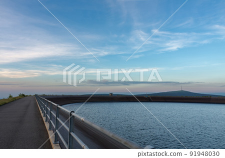 Upper water reservoir of the pumped storage hydro power plant Dlouhe Strane in Jeseniky Mountains, Czech Republic. Top of the Praded mountain behind the lake. During summer evening, sunset Upper water reservoir of the pumped storage hydro power plant Dlouhe Strane in Jeseniky Mountains, Czech Republic. Top of the Praded mountain behind the lake. During summer evening, sunset 91948030