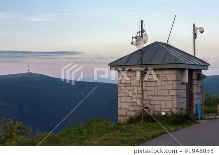 Upper water reservoir of the pumped storage hydro power plant Dlouhe Strane in Jeseniky Mountains, Czech Republic. Top of the Praded mountain behind the lake. During summer evening, sunset. Upper water reservoir of the pumped storage hydro power plant Dlouhe Strane in Jeseniky Mountains, Czech Republic. Top of the Praded mountain behind the lake. During summer evening, sunset. 91948033