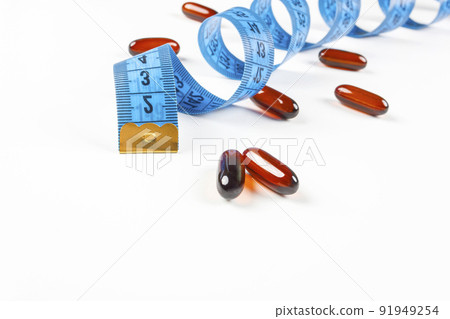 Pile of leptin capsules with blue measuring tape on white background. Concept of losing weight, diet, fat burning, healthy eating. 91949254