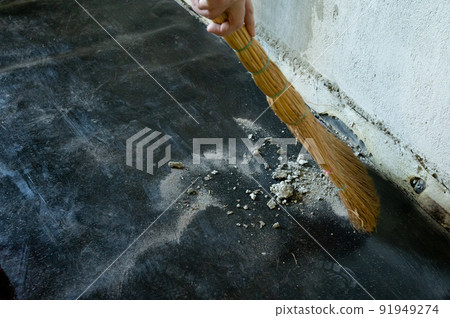 Worker sweeps construction debris with a broom. 91949274