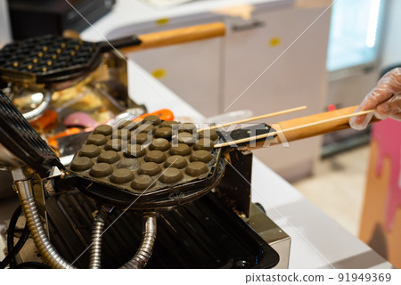 Hong Kong charcoal Waffle is baked on waffle iron machine. 91949369