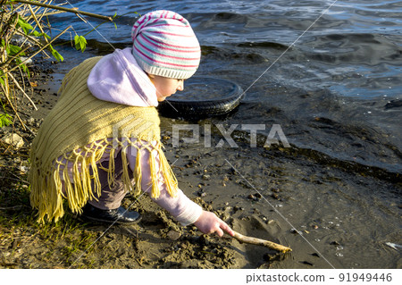 little girl playing with sand on river beach little girl playing with sand on river beach 91949446