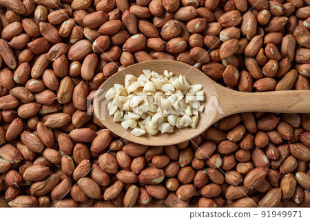 Crushed peanut in a wooden spoon over whole groundnut seeds. Crushed peanut in a wooden spoon over whole groundnut seeds. 91949971
