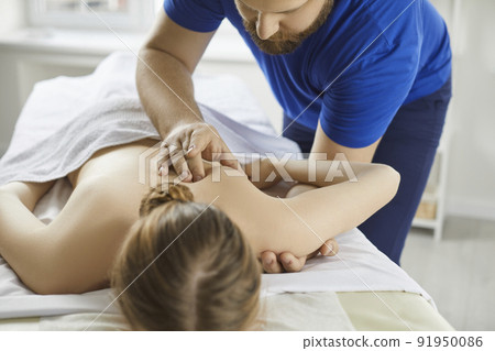 Woman getting back and scapula massage during physiotherapy treatment at modern clinic Woman getting back and scapula massage during physiotherapy treatment at modern clinic 91950086