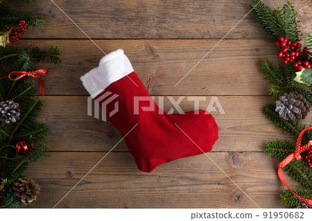 Red Christmas stockings on a rustic wooden wall background with Christmas decoration, fir tree and cone Red Christmas stockings on a rustic wooden wall background with Christmas decoration, fir tree and cone 91950682