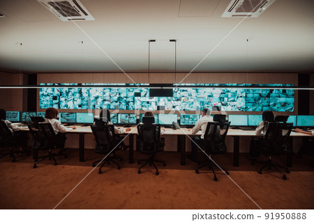 Group of Security data center operators working in a CCTV monitoring room looking on multiple monitors Officers Monitoring Multiple Screens for Suspicious Activities Team working on the System Contr 91950888